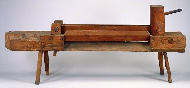 19th-century flax break: a large beam sitting on four legs with another piece of wood on top.